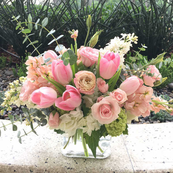 Pink tulips and roses arranged in a clear glass vase