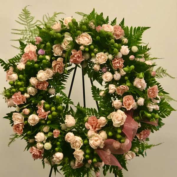 Large floral wreath with pink roses and green berries on a stand