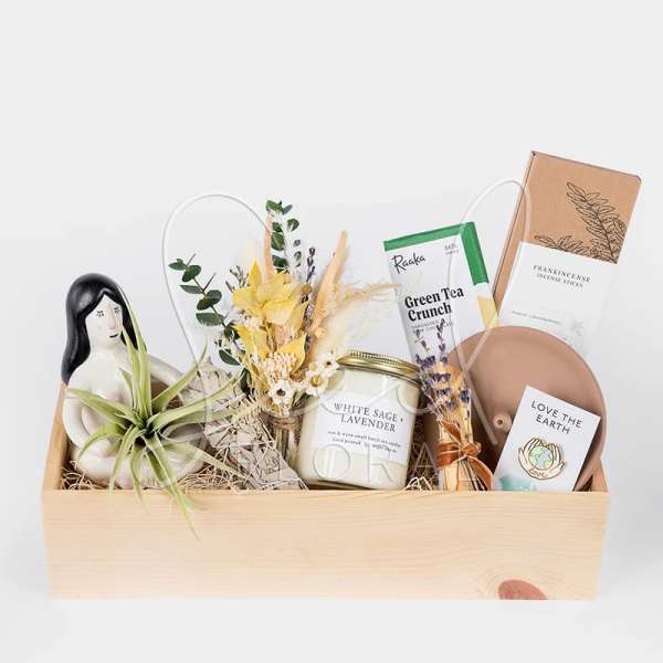 Gift basket with a small floral bundle, candle, tea, incense, and a plant figurine