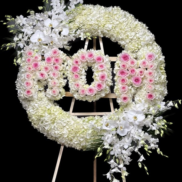 Large floral wreath on an easel with pink roses and white orchids