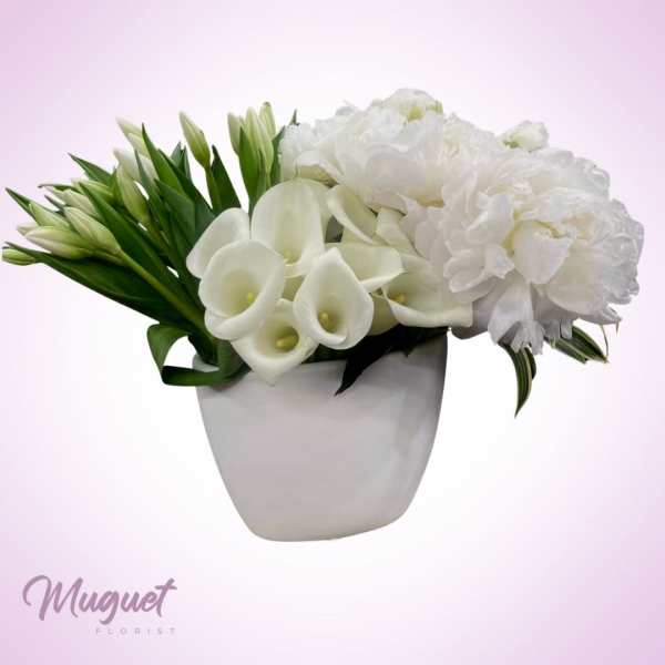 White flowers arranged in a white vase with green buds