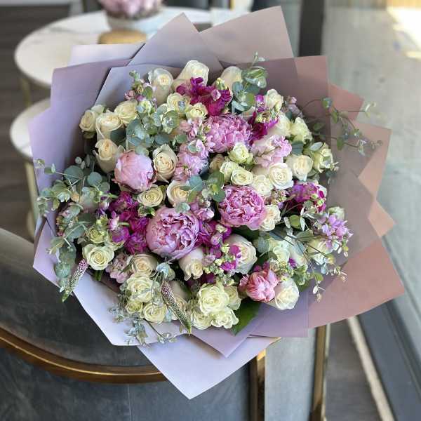 Bouquet of pink and white roses with peonies wrapped in pastel paper