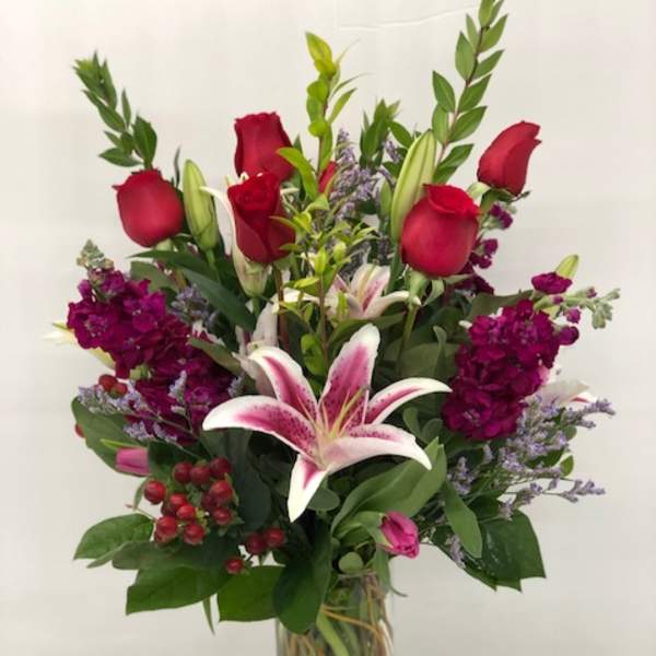 Tall bouquet of red roses and pink lilies in a glass vase