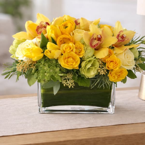 Yellow floral arrangement in a clear rectangular vase