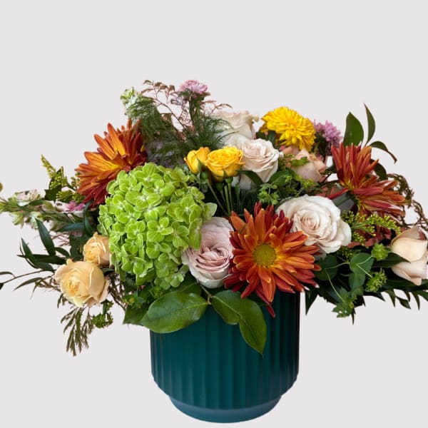 Mixed bouquet of roses, hydrangea, and chrysanthemums in a teal vase