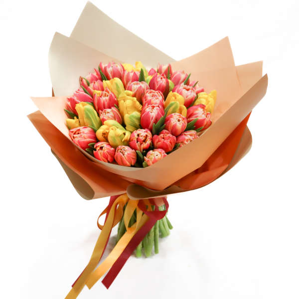 Bouquet of pink and yellow tulips wrapped in tan paper