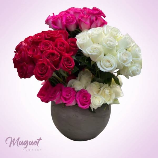 Bouquet of pink, red, and white roses in a dark round vase
