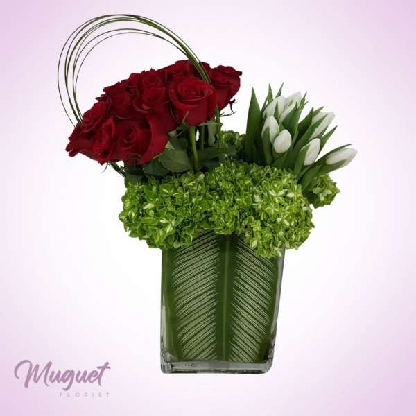Red roses and white tulips arranged in a green glass vase