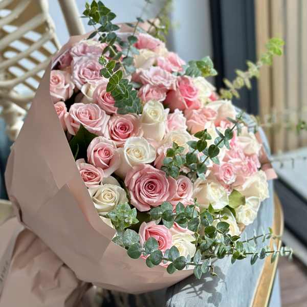 Bouquet of pink and white roses wrapped in blush paper