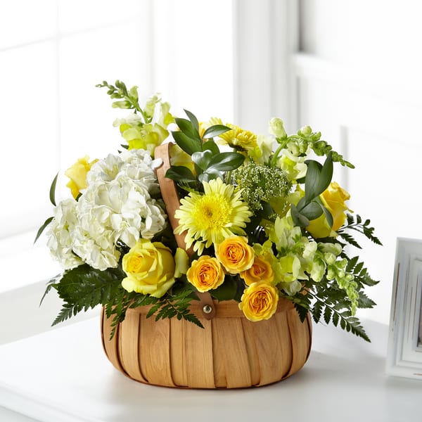 Yellow and white flower arrangement in a woven basket