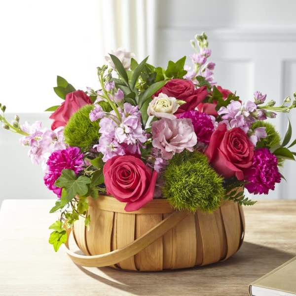 Pink and red roses with carnations in a woven basket