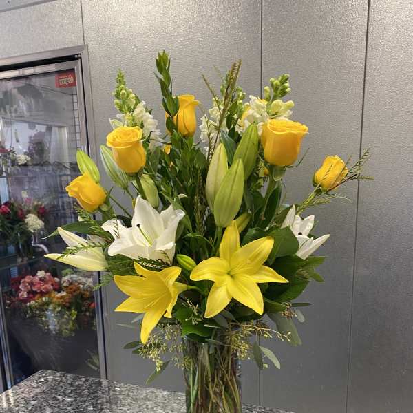 Yellow roses and white lilies in a clear glass vase