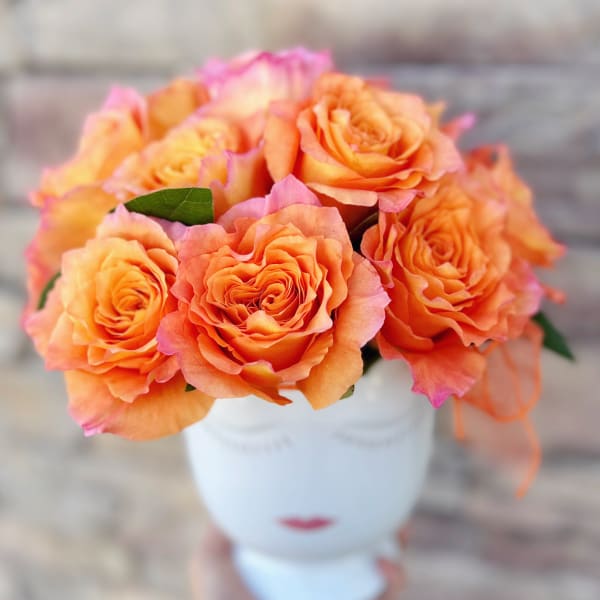 Orange roses arranged in a white vase
