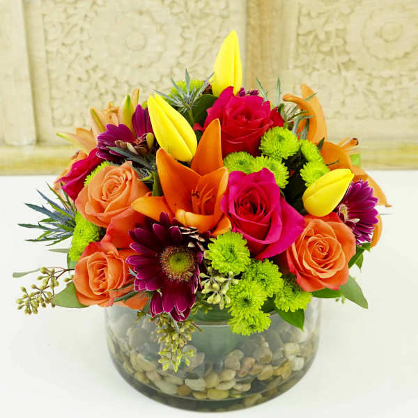 Bright mixed bouquet in a glass bowl vase with stones