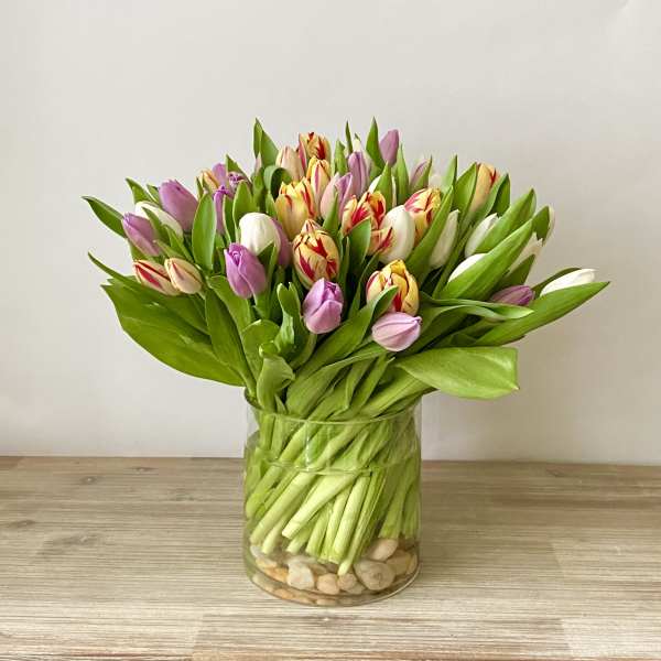 Bouquet of pink, white, and yellow tulips in a clear glass vase