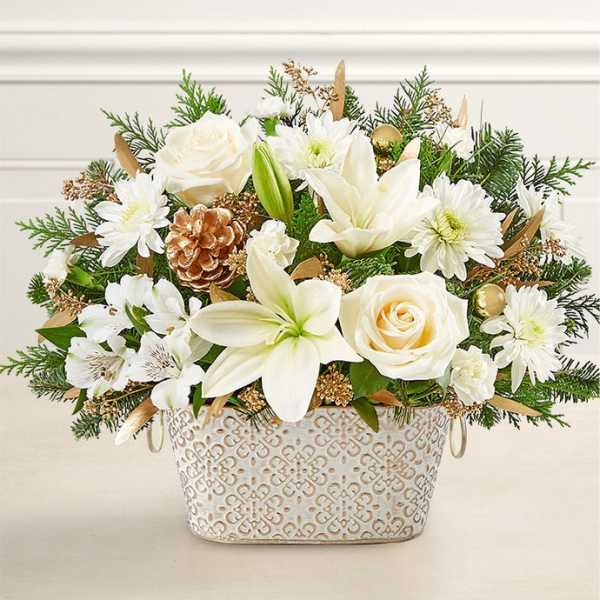 White roses and lilies arranged in a decorative metal basket