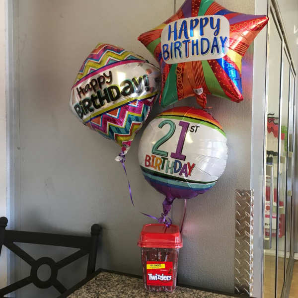 Three birthday balloons with a candy container below