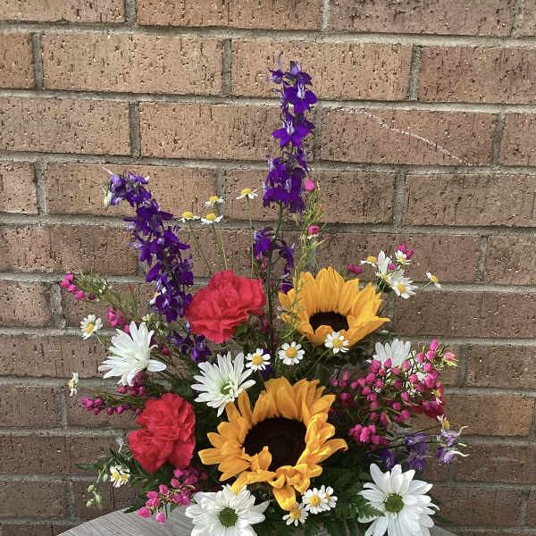 Mixed bouquet with sunflowers, daisies, carnations, and purple spikes in a tin container