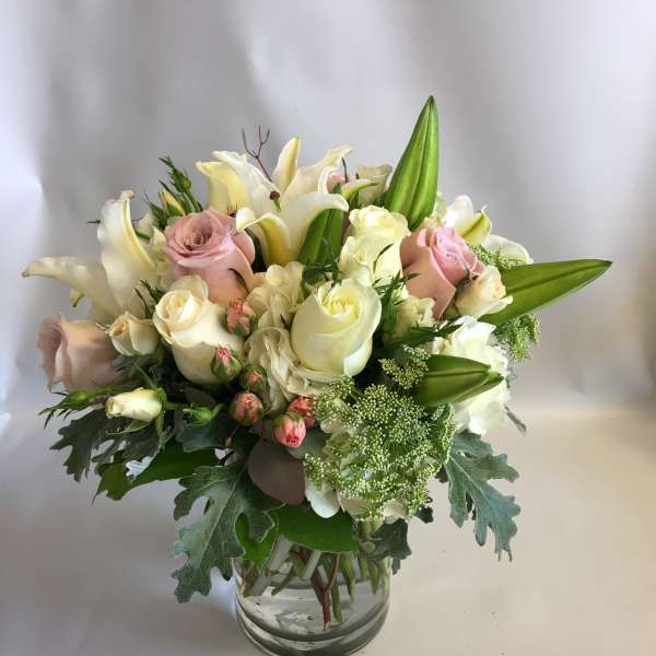 Pink and white roses with lilies in a glass vase
