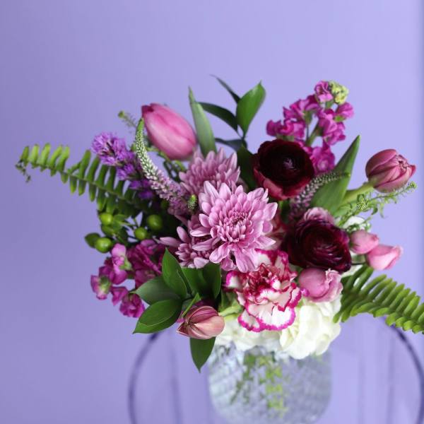 Pink and burgundy flowers arranged in a clear glass vase