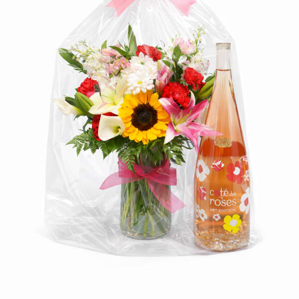 Mixed bouquet in a glass vase beside a bottle of rosé wine