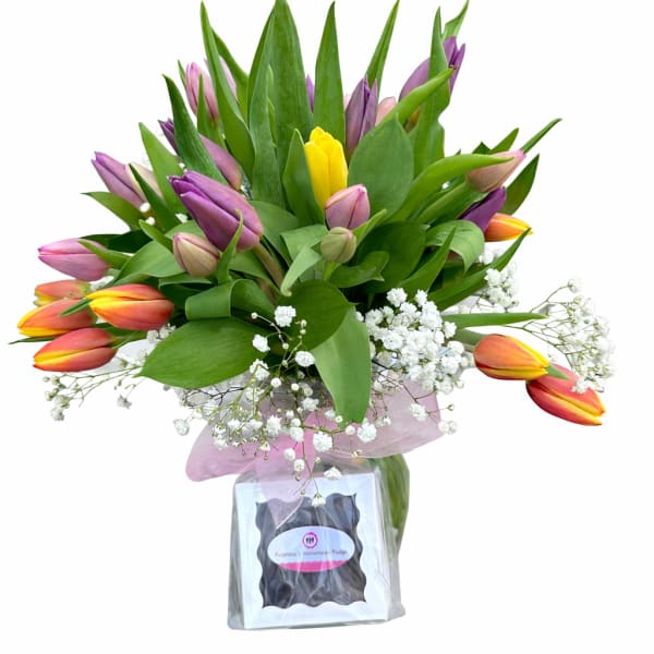 Bouquet of multicolored tulips with baby's breath in a glass vase