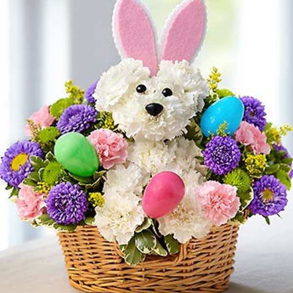 Basket arrangement with a plush bunny and colorful flowers, plus pastel eggs