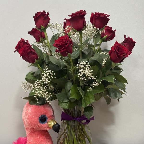 Red roses in a glass vase with a pink plush flamingo