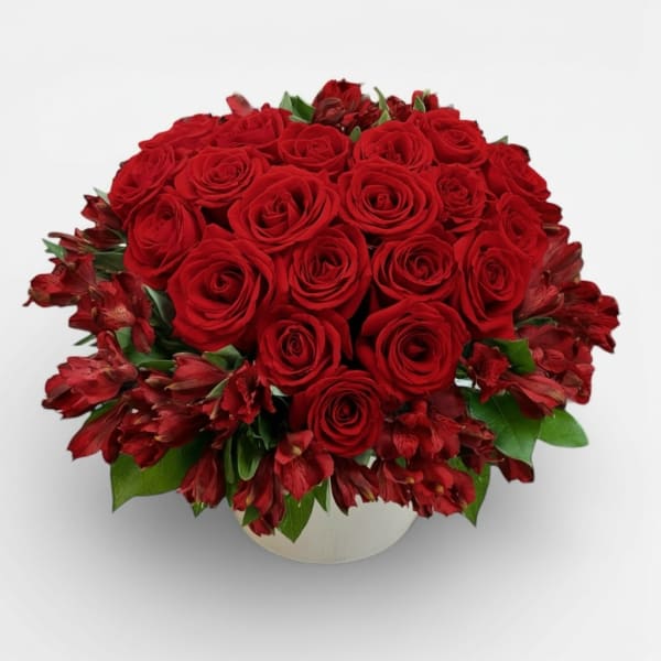 Red roses and red alstroemeria in a white round vase