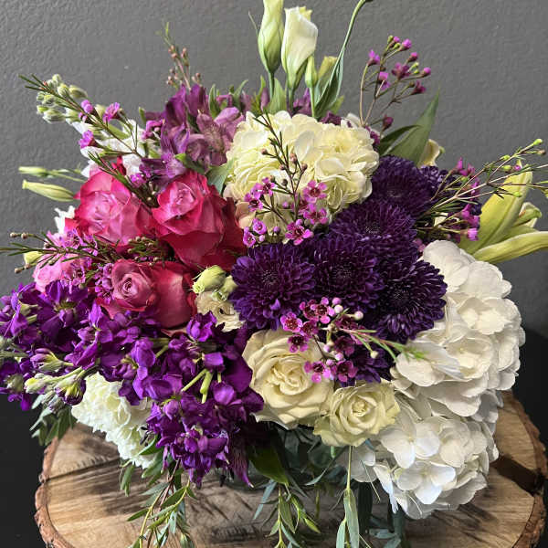 Bouquet of pink, purple, and white flowers on a wooden slab