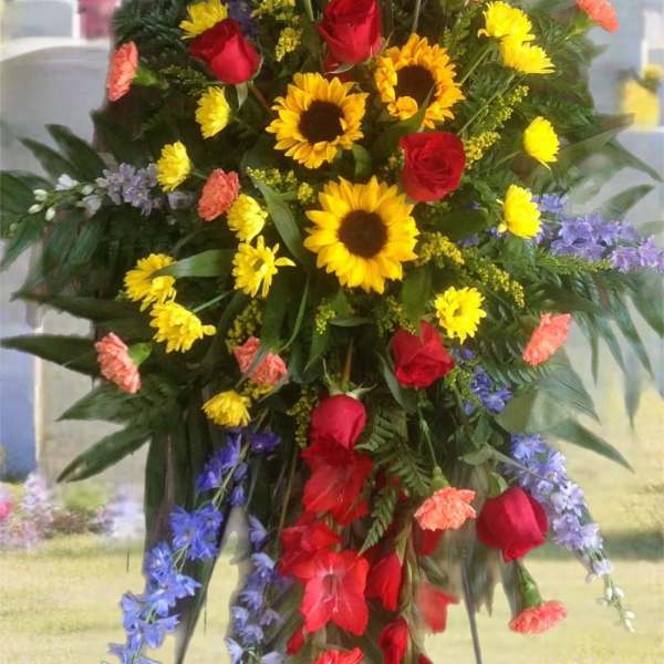 Standing floral spray with red roses, sunflowers, and purple flowers