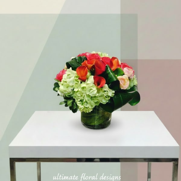 Bouquet of red calla lilies and pale green hydrangeas in a glass vase