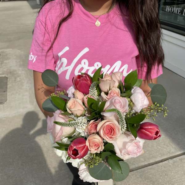 Handheld bouquet of pink roses and red tulips with greenery