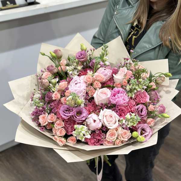 Large bouquet of pink and lavender roses wrapped in cream paper