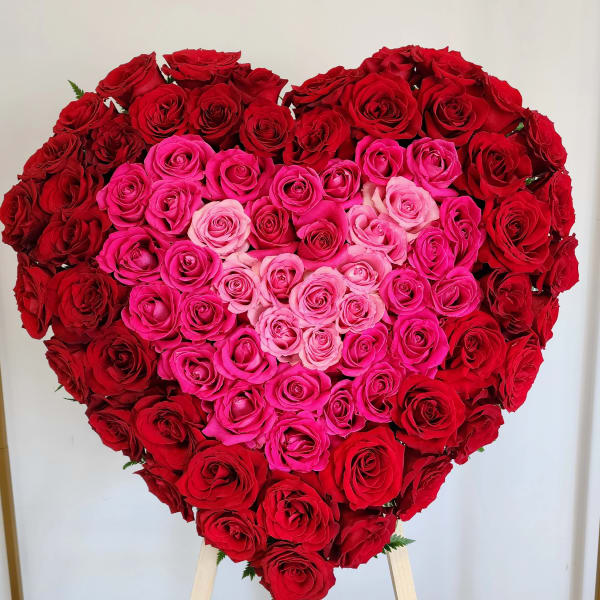 Heart-shaped rose arrangement in red and pink tones on a stand