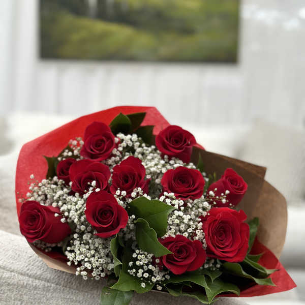 Bouquet of red roses with baby's breath and greenery wrapped in red and brown paper