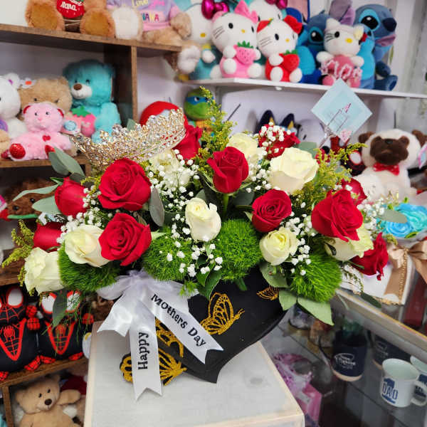 Red and white roses arranged in a black gift box with a crown topper.