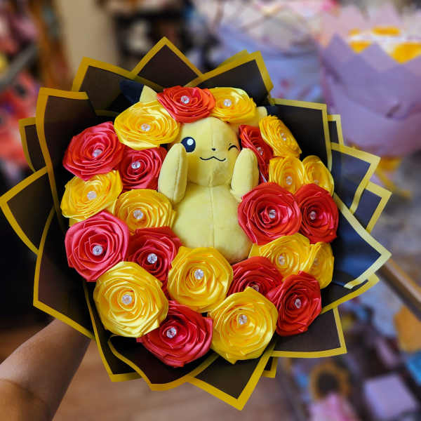 Plush Pikachu surrounded by red and yellow ribbon roses in a bouquet wrap