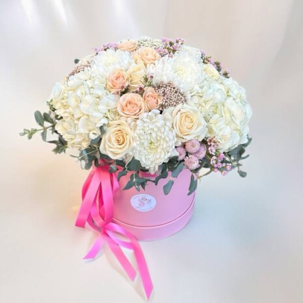 Round bouquet of white and blush flowers in a pink hat box with a ribbon