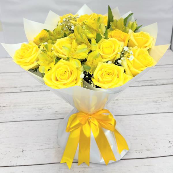 Yellow rose bouquet wrapped in white paper with a yellow ribbon