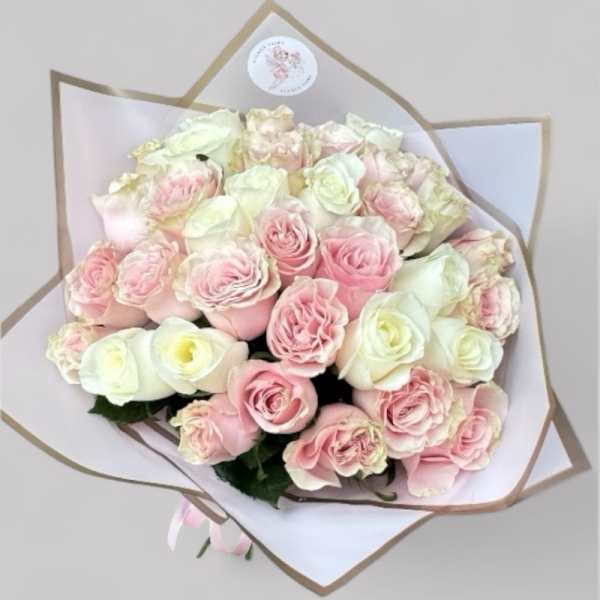 Bouquet of pale pink and white roses wrapped in white paper