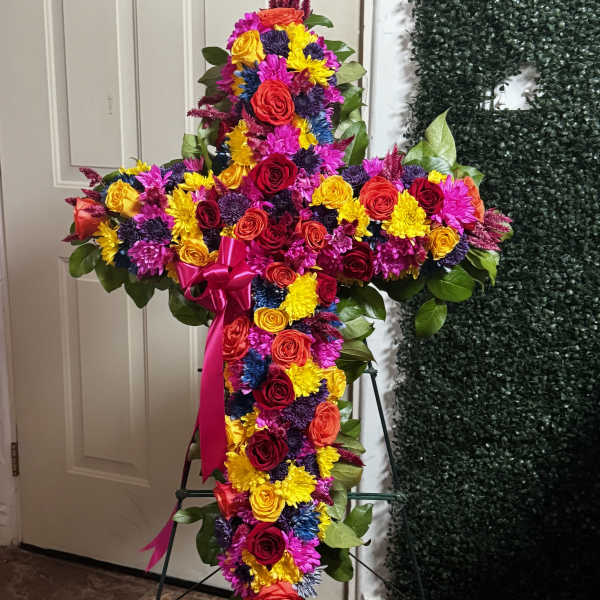 Cross-shaped floral spray with multicolored roses and daisies on an easel