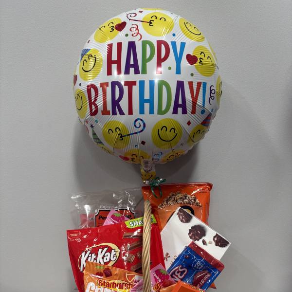 Birthday balloon above a basket of assorted candy
