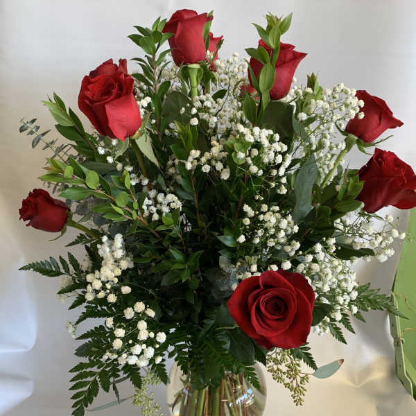 Red roses arranged in a clear glass vase with white baby's breath