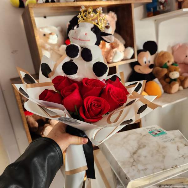 Bouquet of red roses topped with a crowned cow plush