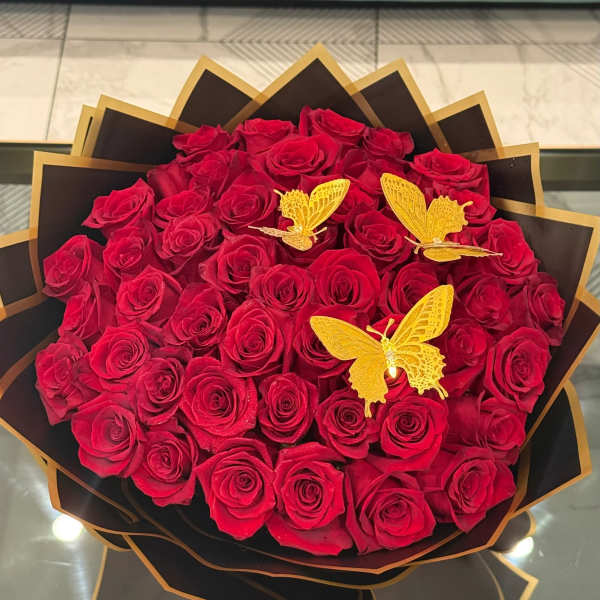 Bouquet of red roses with gold butterfly decorations and black wrapping