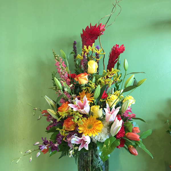 Tall mixed bouquet in a glass vase with lilies, roses, and gerbera daisies