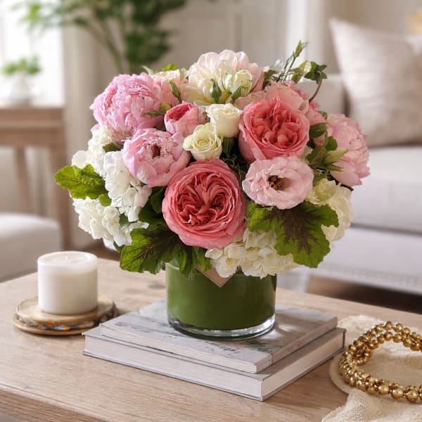 Pink and white flower arrangement in a green glass vase
