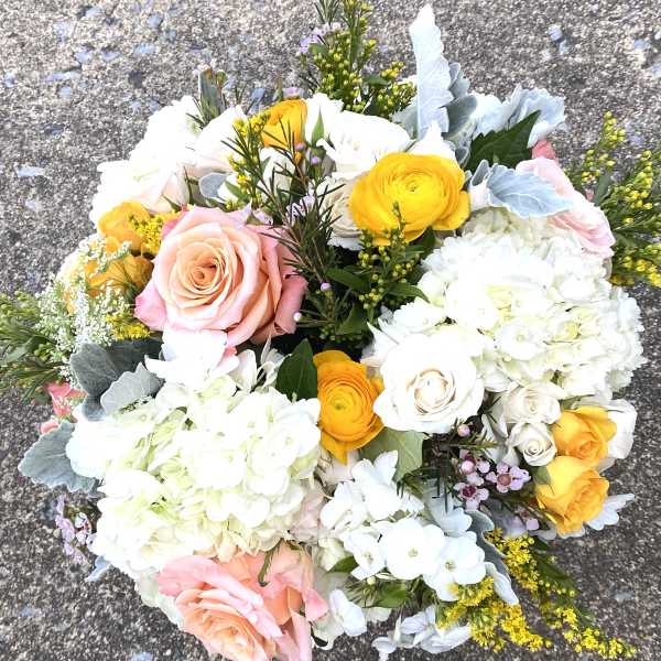 Bouquet of pink and yellow roses with white hydrangeas and mixed blooms