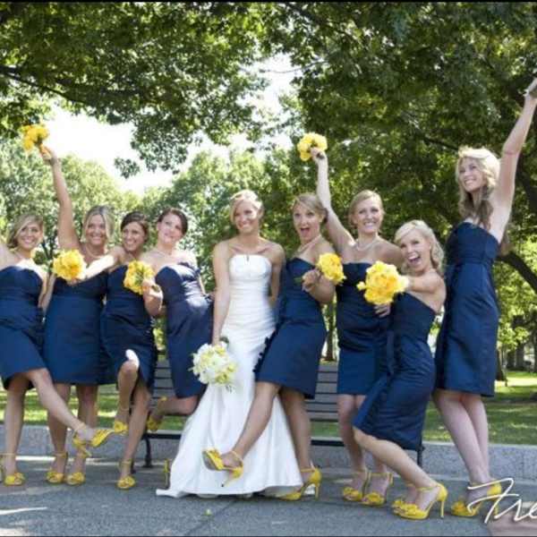 Bride with bridesmaids holding yellow bouquets outdoors